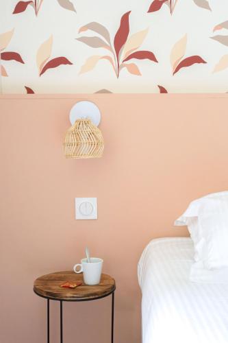 a bedroom with a bed and a table with a cup on it at Eden Park Hotel Restaurant in Pont-lʼÉvêque