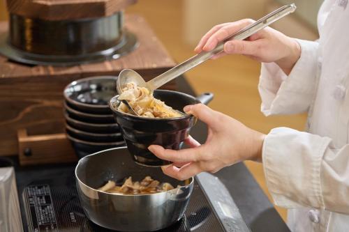 a person holding a bowl of food with a spoon at Kobe Motomachi Tokyu REI Hotel in Kobe