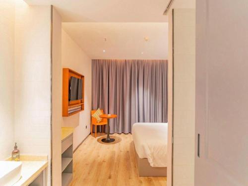 a bedroom with a bed and a television in a room at City Comfort Premier Hotel Xiaogan Anlu Railway Station Dongda Times Square in Xiaogan