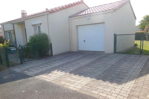 a white garage door on a white house at La Retzienne - Parking - Jardin in Prigny