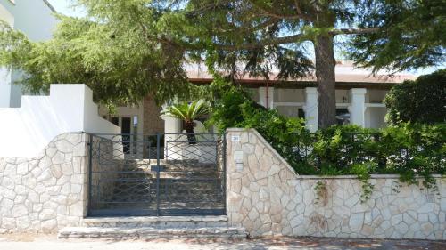 un cancello di fronte a una casa con una pianta di Affitta camere ALMA MATER a Castrignano del Capo