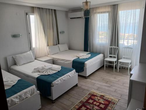 a hotel room with two beds and a chair at Huzur Hotel in Siğacık