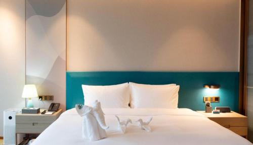 a bedroom with a white bed with a green headboard at Zhuhai Hongsanyi Hotel in Zhuhai