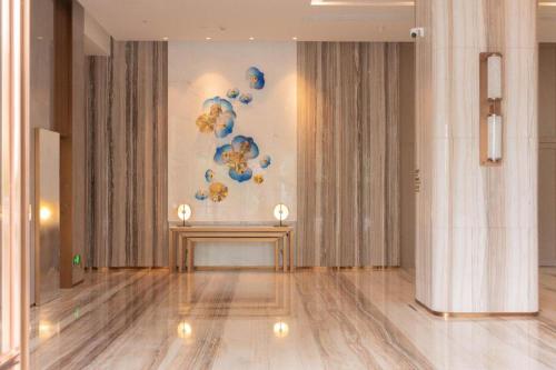 a hallway with two tables and a painting on the wall at Zhuhai Hongsanyi Hotel in Zhuhai