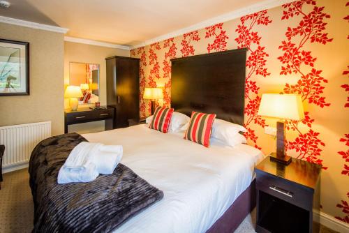a bedroom with a large white bed with red wallpaper at Woodlands in Windermere