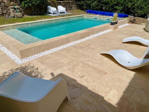 a swimming pool with two white chairs next to it at Maisonnette Aix en Provence in Aix-en-Provence