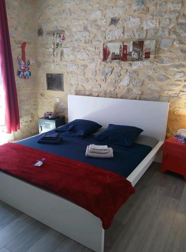 un lit dans une chambre avec un mur en pierre dans l'établissement Mas provençal, à Mézoargues