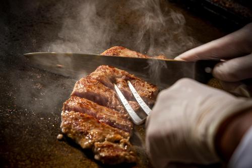 a person cooking meat on a grill with a spatula at Highland Resort Hotel & Spa in Fujiyoshida