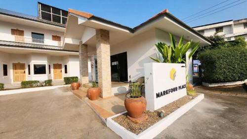 a white house with plants in front of it at Mark Four Place Hotel in Phrae