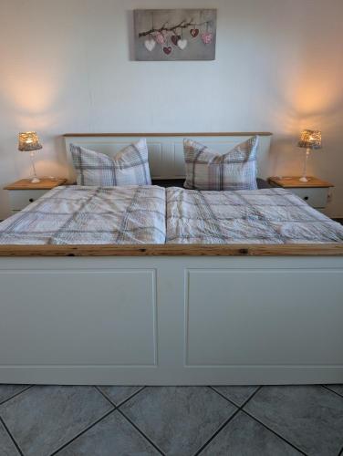 a large white bed with two lamps on two tables at Hygge am See in Aventoft