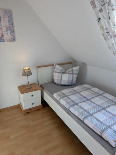 a bedroom with a bed and a lamp on a night stand at Hygge am See in Aventoft