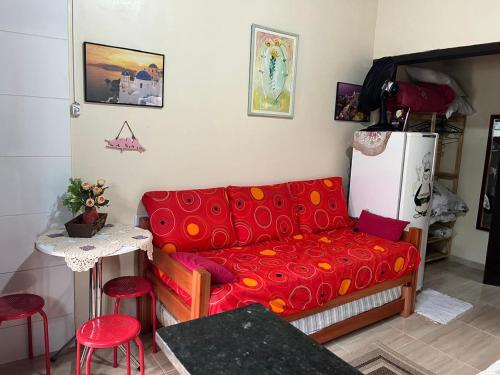 Una sala de estar con un sofá rojo y una mesa. en Kitnet Martin de Sa para casal, en Caraguatatuba