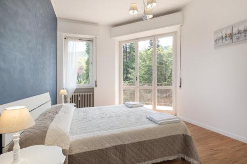 ein weißes Schlafzimmer mit einem Bett und zwei Fenstern in der Unterkunft Costa Azzurra by Impero House in Stresa