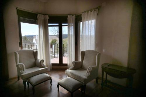 a living room with two chairs and a table and windows at Hotel Rural Los Abriles in El Toro