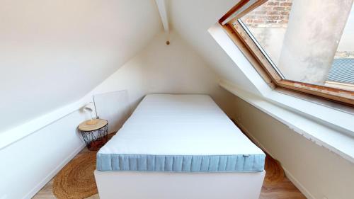 une petite pièce avec un lit et une fenêtre dans l'établissement Magnifique appartement Bastion, au Havre