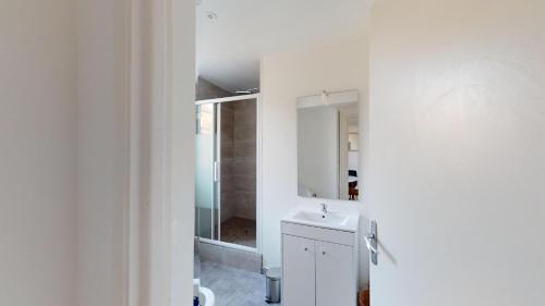 une salle de bain blanche avec un lavabo et un miroir dans l'établissement Magnifique appartement Bastion, au Havre