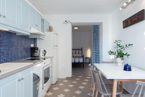 a kitchen with white cabinets and a table with chairs at Rocks and Waves Sifnos in Kamarai