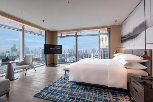 a bedroom with a large bed and a flat screen tv at Courtyard by Marriott Guangzhou Pazhou in Guangzhou