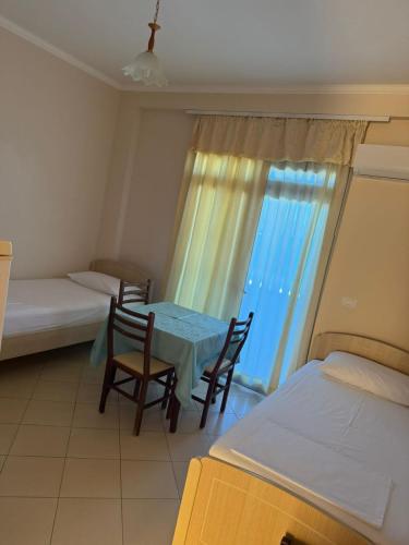 a room with a table and two beds and a window at Sunny beach Jonufer in Vlorë
