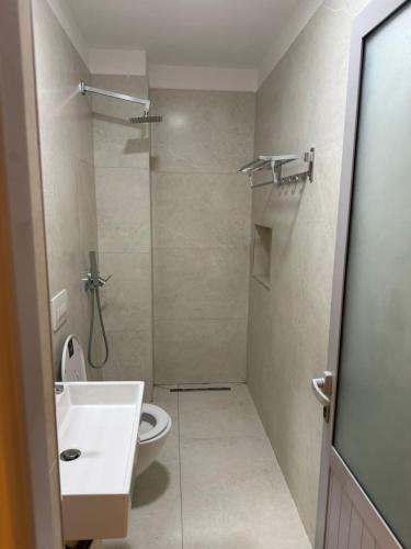 a bathroom with a toilet and a sink and a shower at Sunny beach Jonufer in Vlorë