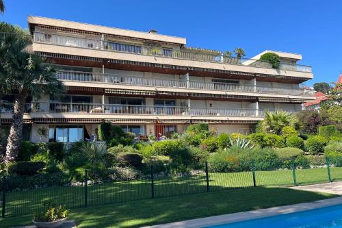 un grand bâtiment avec un jardin en face dans l'établissement Appartement Costebelle vue mer - Welkeys, à Cannes
