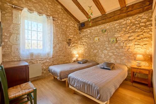 two beds in a room with a stone wall at La Mijotière - maison avec piscine et grand jardin in Thénac