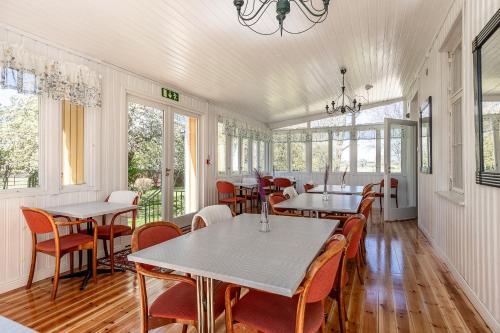 a dining room with tables and chairs and windows at Mjällbyhus Pensionat & Stugby in Sölvesborg
