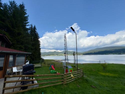 a house with a fence next to a body of water at Villa Raiski kyt in Dospat
