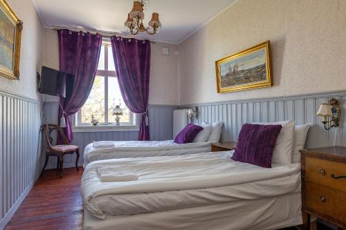 two beds in a hotel room with purple curtains at Mjällbyhus Pensionat & Stugby in Sölvesborg