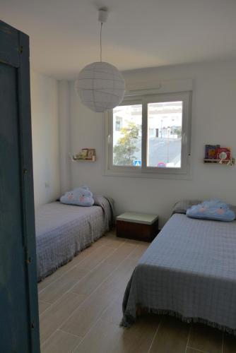 a bedroom with two beds and a window at Casa Aurora Vejer in Vejer de la Frontera
