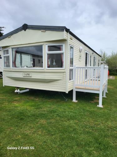 a white caravan parked in a yard with a porch at Home from home in Little Holland