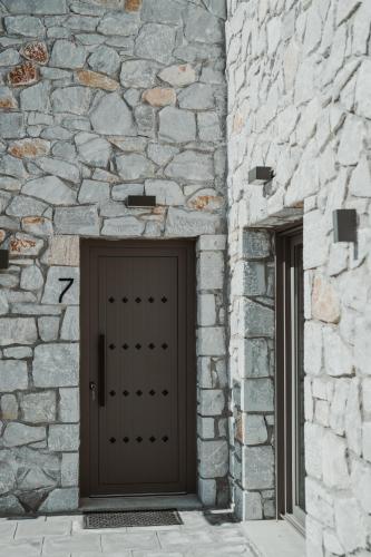 a brown door in a stone building with two windows at Ktima Papadopoulou in Krionérion