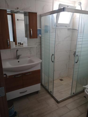 a bathroom with a glass shower and a sink at Huzur Hotel in Siğacık
