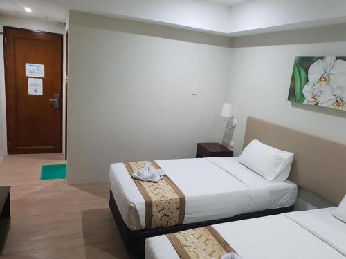 a hotel room with two beds and a door at Hotel Fleur de Liz in Panglao