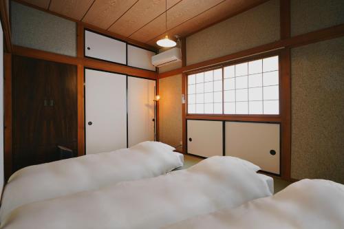 a room with three beds and a window at 塩釜バケーションレンタル Sora No Oka in Shiogama