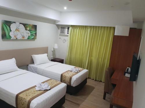 a hotel room with two beds and a desk at Hotel Fleur de Liz in Panglao