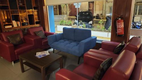 a waiting room with a blue chair and red chairs at Hotel Riomar in Lagos