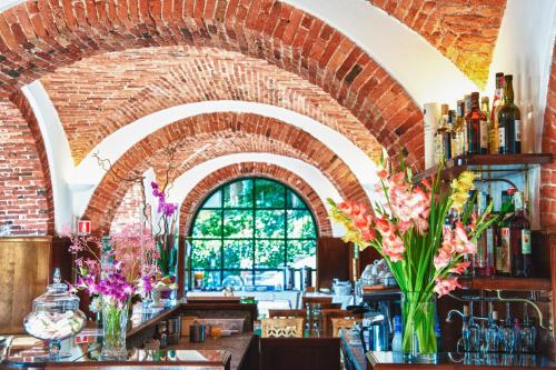 a bar with a brick wall and vases of flowers at Relais Casali della Cisterna in Belgirate