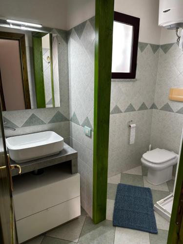 a bathroom with a sink and a toilet and a mirror at Su Coru Budoni in Budoni