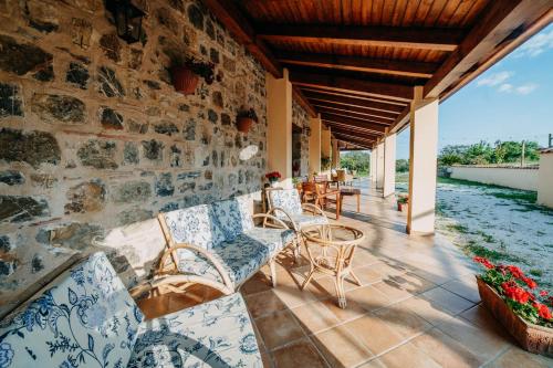 a patio with chairs and tables on a stone wall at Tenuta Le Tre Rose in Vibonati
