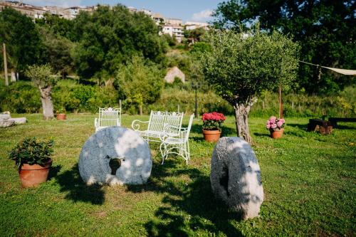 a garden with white chairs and rocks in the grass at Tenuta Le Tre Rose in Vibonati