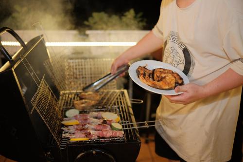 a person holding a plate of food on a grill at Mountain Nest Villa Dalat - BBQ, Cloud Hunting, Camping in Da Lat