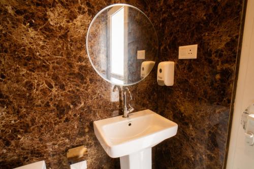 a bathroom with a sink and a mirror at Ila by Aaryam, Kanatal in Chamba