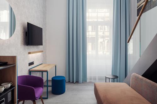 a living room with a bed and a purple chair at EA Hotel Moment Self Check-In in Prague