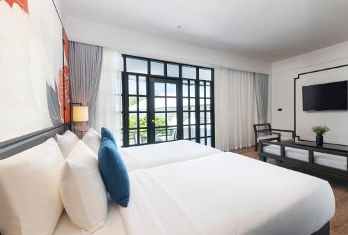 a bedroom with a large white bed and a flat screen tv at Indochina Hotel in Aranyaprathet