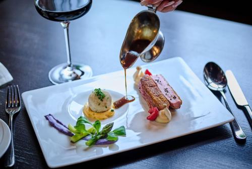 a white plate with food on a table with wine glasses at Hotel Wutzschleife in Rötz