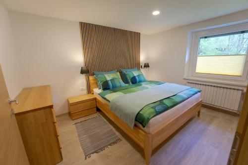 Un dormitorio con una cama con almohadas azules y una ventana. en Apartma Pr'kovač, en Bohinjska Bistrica