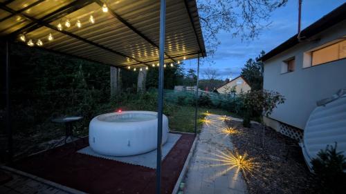 a bath tub sitting under a pergola with lights at Maci-Ház in Orfű
