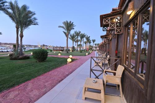 a building with chairs and a walkway with palm trees at Xperience Golden Sandy Beach in Sharm El Sheikh