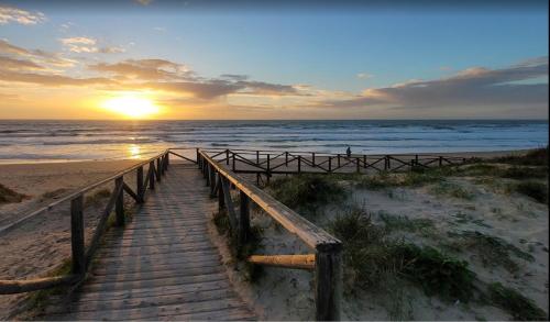 a wooden path to the beach with the sunset in the background at Rinconcito en el Paraíso Costa Ballena in Costa Ballena
